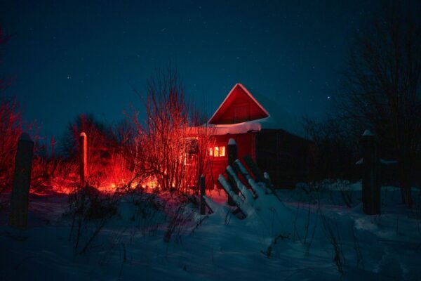 Luminen mökki lämpimine ikkunavaloineen talviyössä